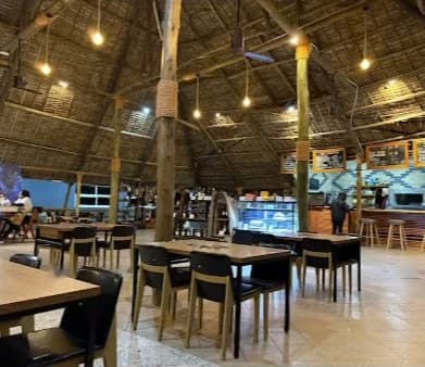 Rows of wooden tables under the thatched roof, with the bar and display counter behind