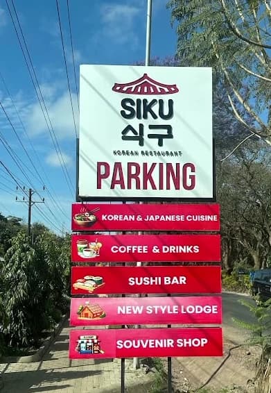 SIKU roadside sign reading Korean restaurant, parking, Korean and Japanese cuisine, coffee and drinks, sushi bar, new style lodge and souvenir shop