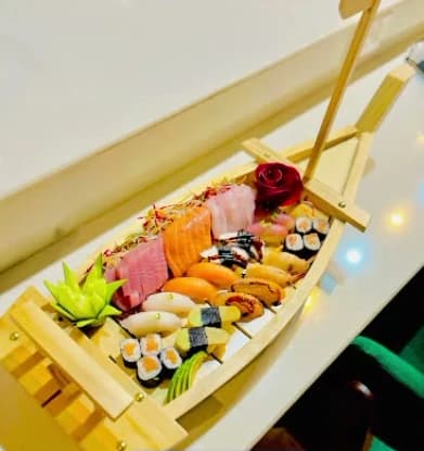 A wooden sushi boat loaded with salmon and tuna sashimi, nigiri and maki rolls